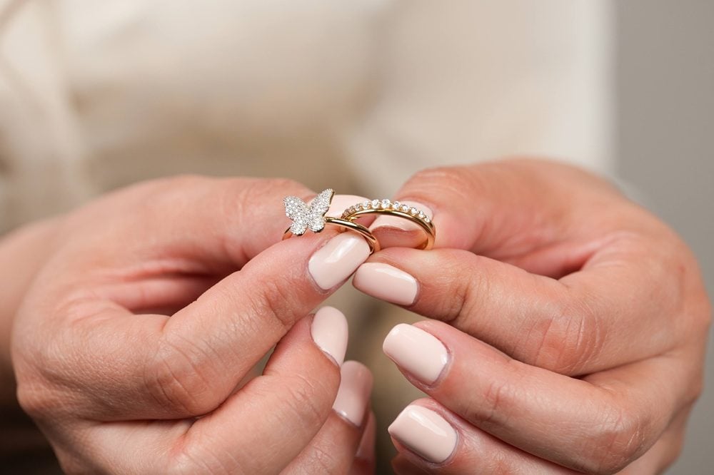 hands holding a butterfly diamond ring and diamond band